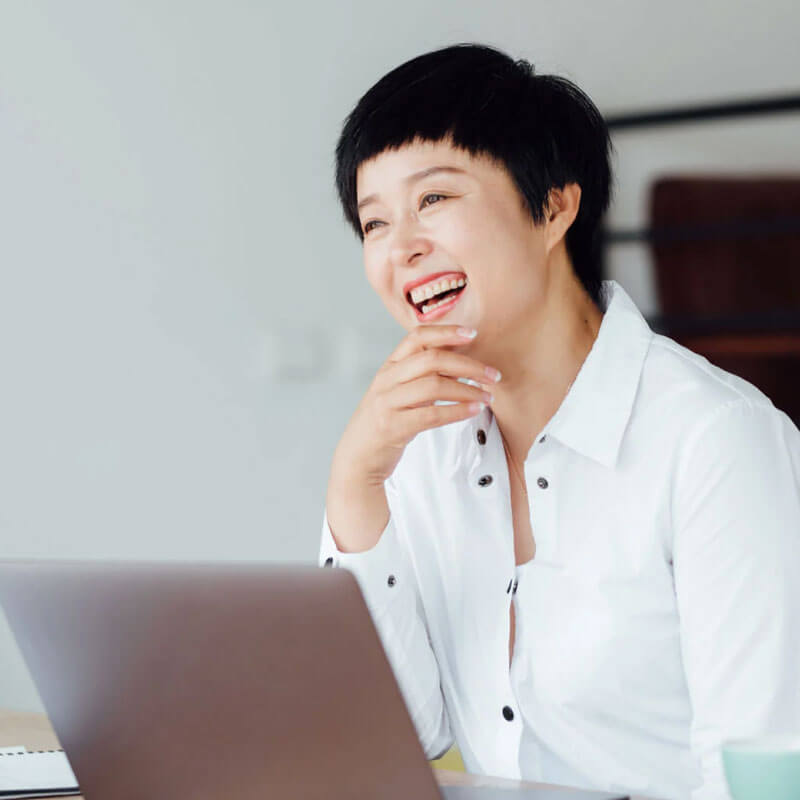 Woman smiling and using laptop as a image of Scilife's customers.
